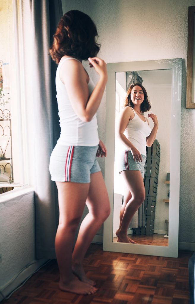 amor próprio-autoestima-diferença-depyl action-mulher-feliz-olhando-no-espelho